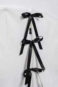 Detail of white top featuring three black satin bow ties and silver eyelets for women