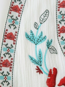 Detail of white cotton vest showing ethnic floral embroidery and seersucker texture
