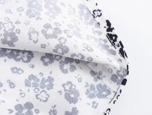 Macro detail of high-quality stitching and black floral print on white woven fabric