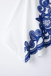 Détail de la broderie bohème et de la texture du tissu en coton sur chemise blanche