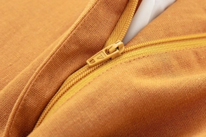 Macro close-up of high-quality nylon zipper on orange linen blend fabric top detail