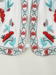 Detail of vibrant floral and geometric embroidery on a white bohemian sleeveless vest