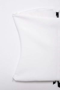 Detail of white off-shoulder top featuring a sleek side hidden zipper and woven fabric texture