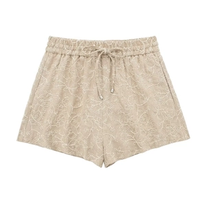 Close-up of women's beige summer shorts with floral embroidery and drawstring waist