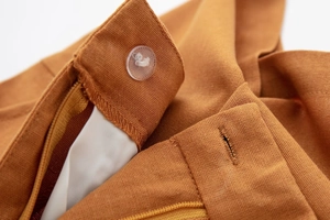 Macro view of terracotta linen blend shorts featuring a clear button and zipper closure