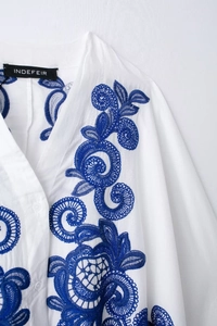 Vue détaillée de la broderie paisley bleue de qualité sur un chemisier en coton blanc