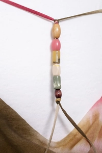 Dettaglio macro dell'abito midi tie-dye bohémien con spalline di perline e seta leggera
