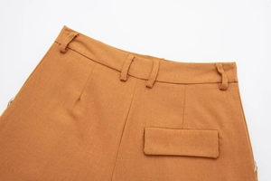 Detail of ochre linen blend trousers showing waist loops and decorative flap pocket