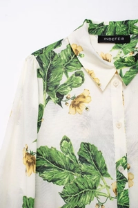Close-up of lightweight white shirt featuring vibrant green leaf and yellow floral prints