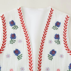 Women's white sleeveless vest with blue floral embroidery and red herringbone ribbon trim
