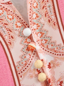 Dettaglio del vestito con stampa paisley e bottoni rivestiti in tessuto dai colori misti