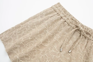 Close-up of khaki elastic waistband with white floral embroidery and drawstring detail