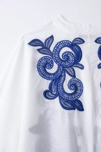 Vue détaillée de la broderie florale bleue sur le tissu en coton blanc du col de chemise