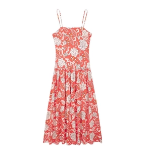 Close-up of coral red floral summer dress featuring large white prints and pleated fabric