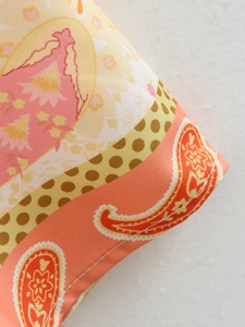 Dettaglio di un abito estivo con scollo a V e stampe paisley e pois colorati