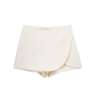 Detail view of high waist asymmetric beige skort with side zipper and smooth tailoring