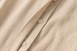 Detailaufnahme von Leinenhemd mit Perlmuttknöpfen und natürlicher Stoffstruktur