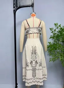 Dettaglio completo di set in cotone beige con ricami floreali e bordi ondulati rifiniti