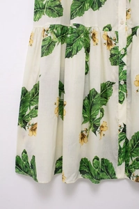Detail of floral summer dress featuring green leaf prints and white resin buttons