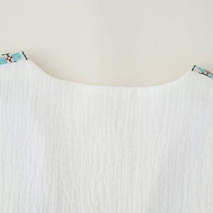 White sleeveless top with ethnic geometric embroidery on the shoulders and crew neck