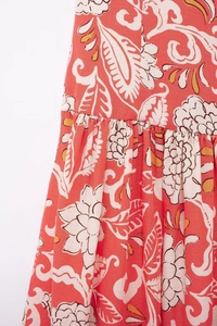 Close-up of floral paisley print on coral red pleated woven fabric with cotton-linen texture