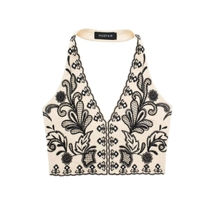 Women summer halter crop top with black floral embroidery on cream fabric flat lay