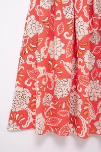 Close-up of coral red floral print fabric with vintage patterns on linen summer dress