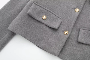 Detailaufnahme der grauen Wolljacke mit strukturierter Textur und goldenen Metallknöpfen
