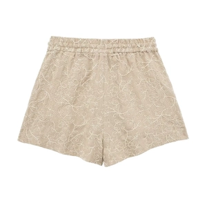 Close-up of white floral embroidery and elastic waistband on beige cotton linen shorts