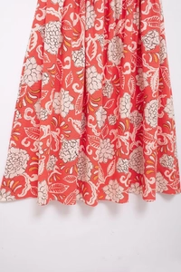 Detailed close-up of orange floral summer dress fabric with beige flower patterns