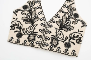 Detail of bohemian halter top showing black floral embroidery and mirror sequins on linen fabric