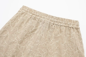 Detail of khakie shorts featuring elastic waist and intricate white floral embroidery on linen
