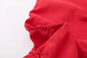 Close-up of deep red top fabric featuring a matching invisible zipper and elastic seams