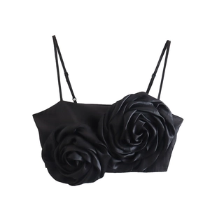 Close-up of black satin crop top featuring 3D floral rose details and thin straps