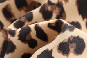 Macro shot of high-quality leopard print satin fabric with soft draped texture