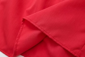 Macro shot of precise stitching and red woven cotton-linen texture on the top hem