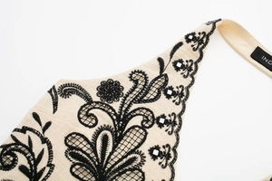 Detailed macro view of beige linen fabric with black lace embroidery and sequins