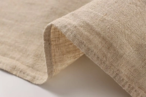 Makro-Detail von natürlichem Leinenstoff in Haferflockenfarbe mit feiner Saumnaht-Textur