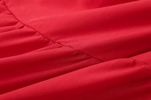 Detail shot of the red cotton fabric with ruffled stitching and fine woven texture