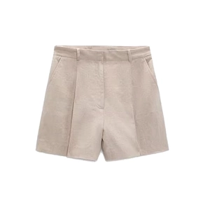 Detail of beige linen shorts with pleats, side pockets, and natural fiber texture