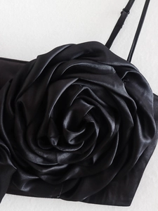Detail of a black satin top featuring a large handmade 3D floral rose decoration