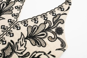 Detailed view of beige fabric with black floral embroidery and sequin embellishments