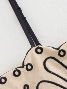 Dettaglio del tessuto dell'abito estivo beige con ricamo nero e spallina regolabile