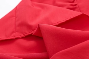 Detail shot of red slim-fit top showing premium fabric texture and neat stitching lines