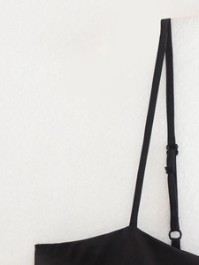 Close-up detail of adjustable thin spaghetti straps with sliders on a black summer top