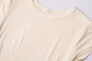 Close-up of cream ribbed knit fabric showing the crew neckline and size L label