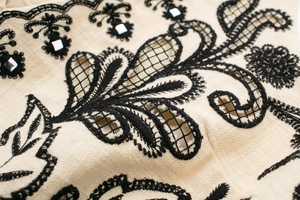 Detailed embroidery with paisley patterns and silver sequins on beige linen fabric