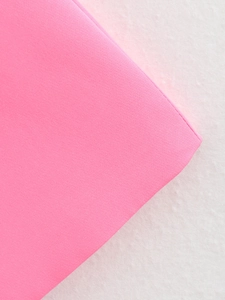 Detail of bright pink knit fabric texture with smooth stitching on a neutral background