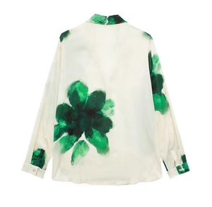 Détail d'un chemisier en satin avec motifs floraux verts et texture drapée
