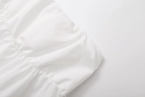 Close-up detail of white ruched fabric texture with elastic smocking and pleated edges